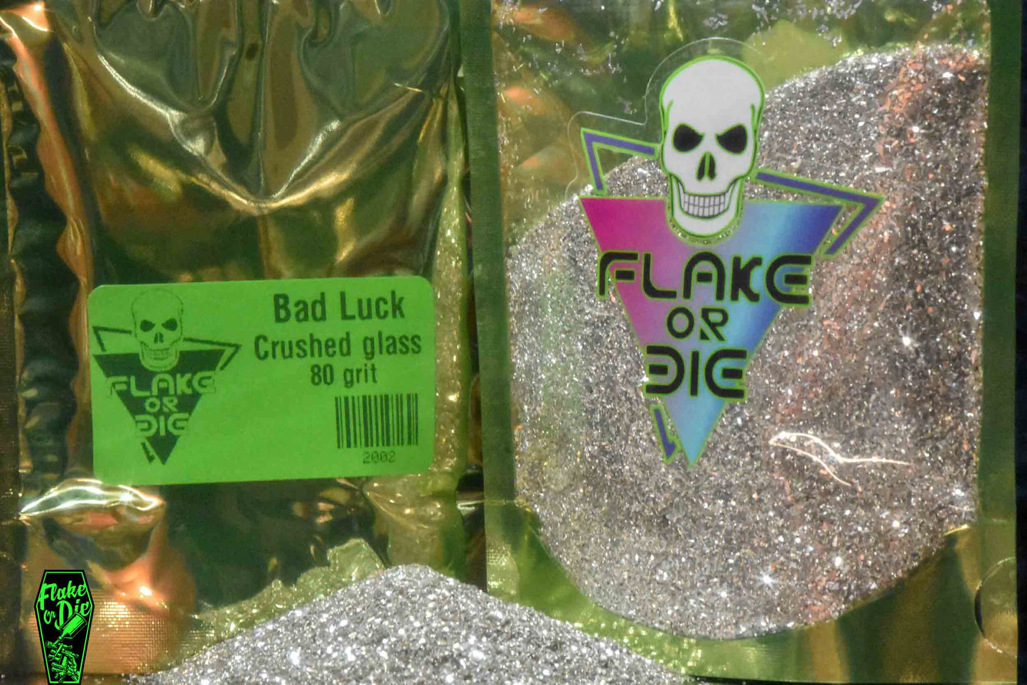 Macro photography product shot of silver glass particles in a clear window foil package with company logo.