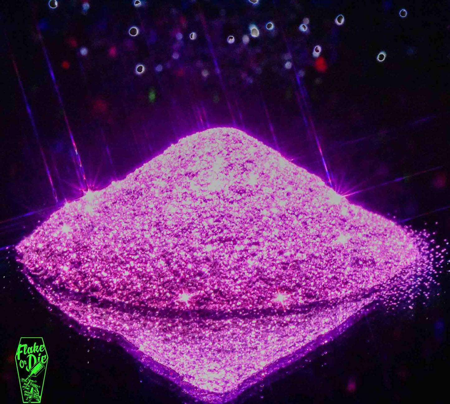 Macro photography of a small pile of blended magenta metal flake particles. Distinct glitter flares on the metal flake and a complementary background of silver/black and red bokeh.
