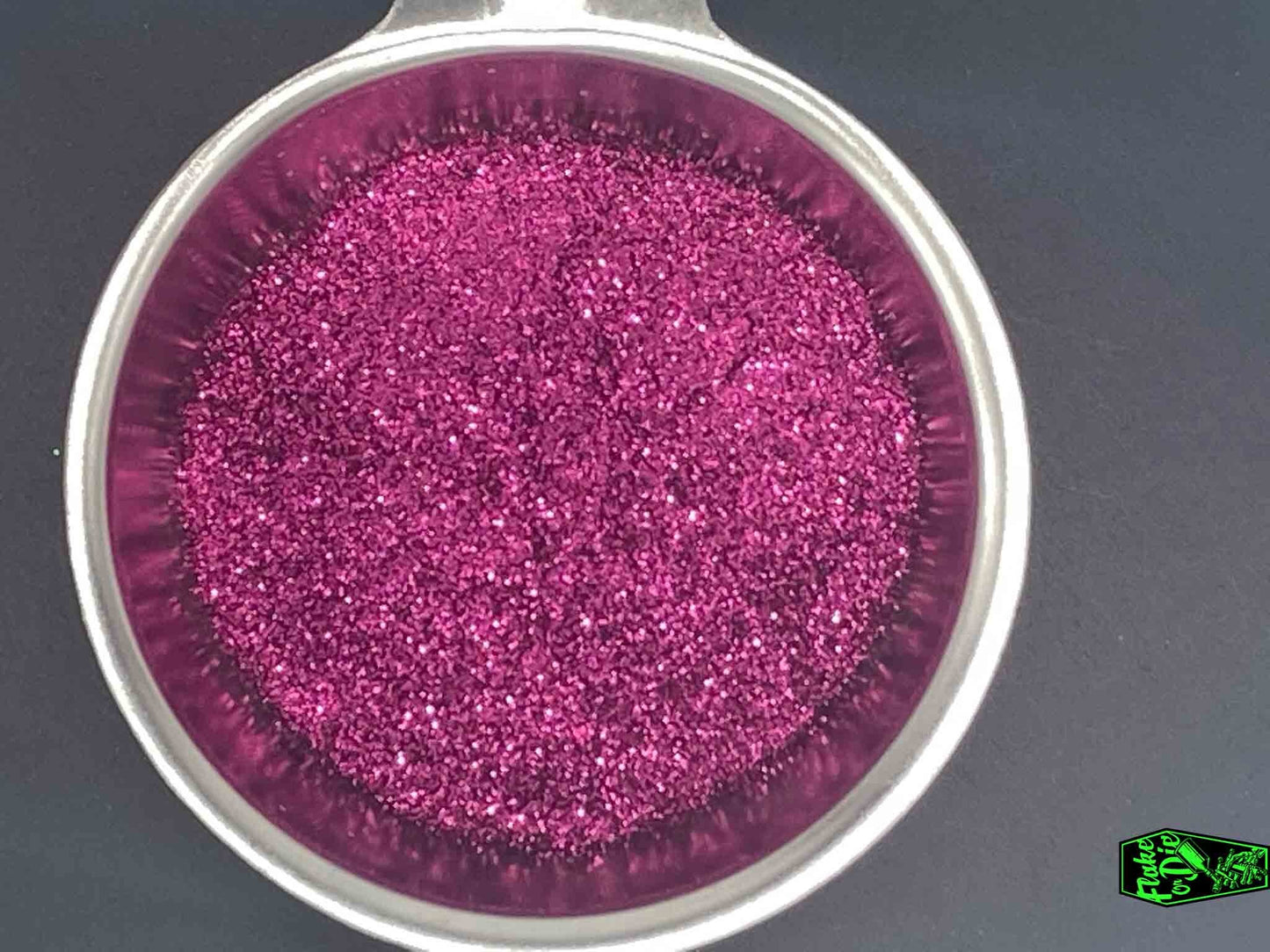 Direct macro photography shot of magenta metal flake particles in a stainless-steel bowl.