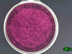 Direct macro photography shot of magenta metal flake particles in a stainless-steel bowl.