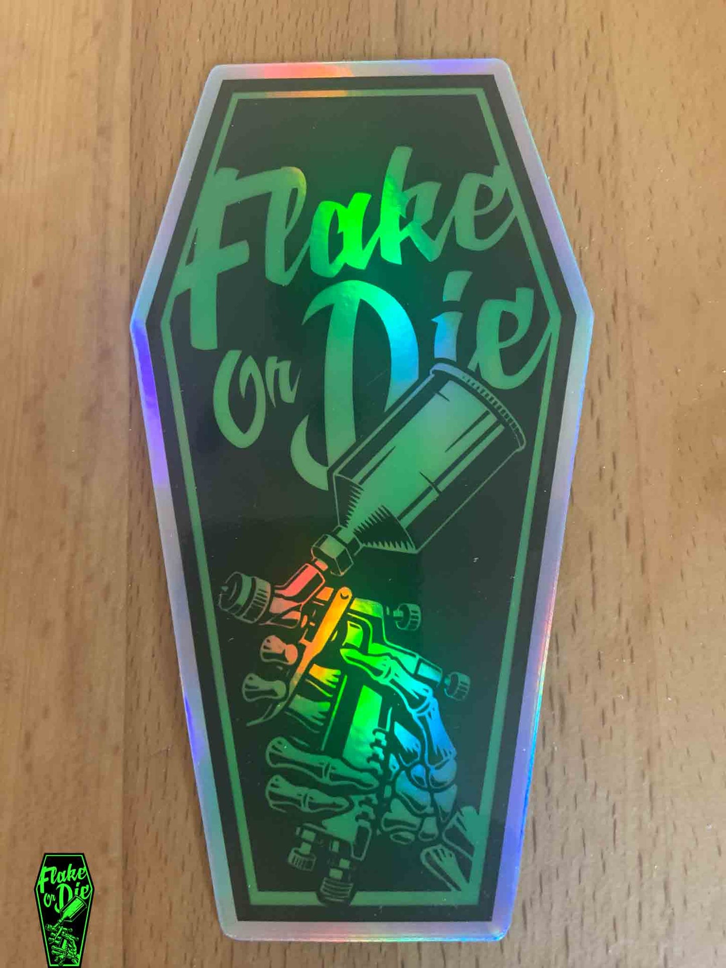 The Flake Or Die green color shifting holographic coffin logo on a black background. This one is 5" x 2.75".