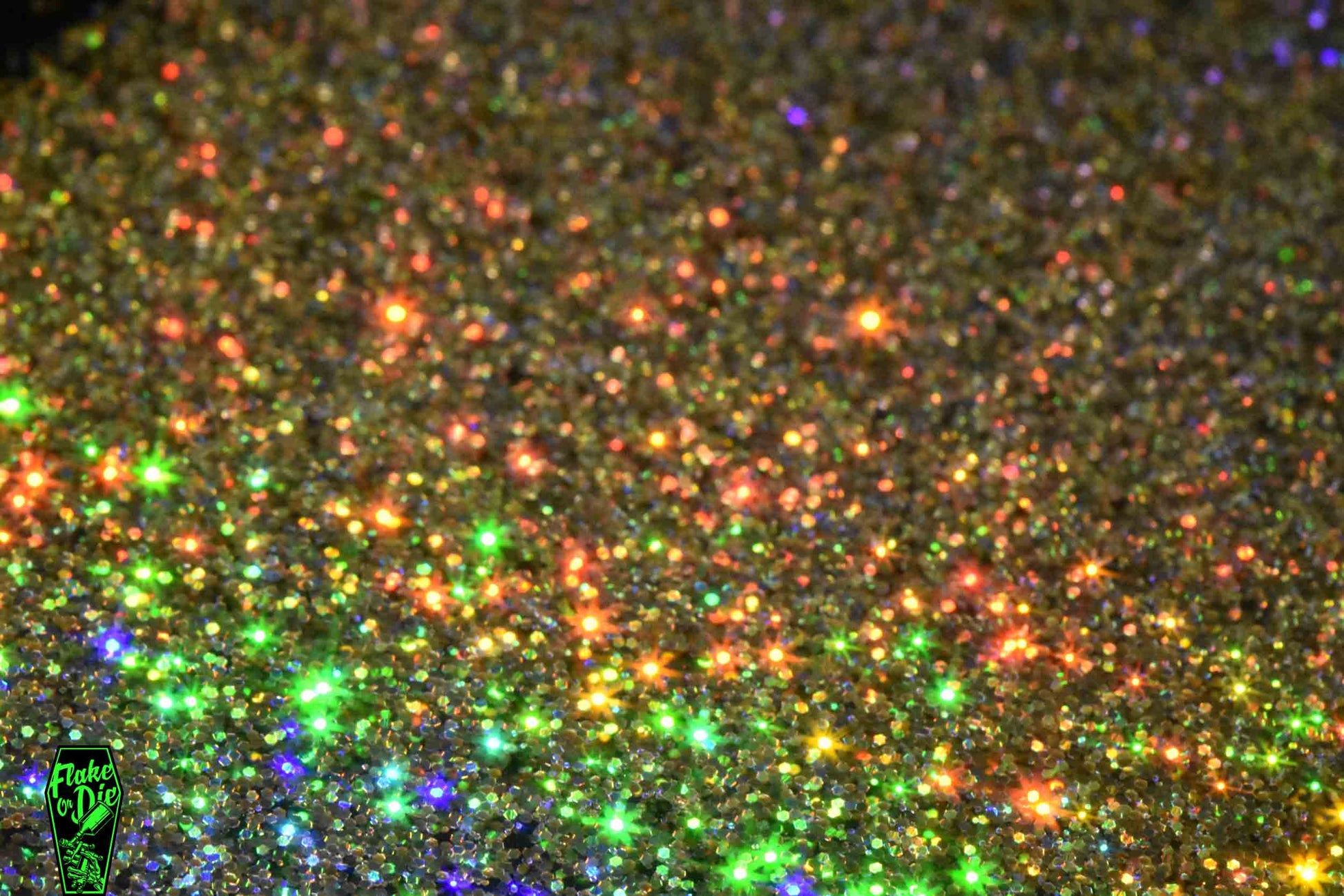 Macro photography of blended gold holographic metal flake particles. Distinct glitter flares of gold, purple, green and orange on the metal flake.