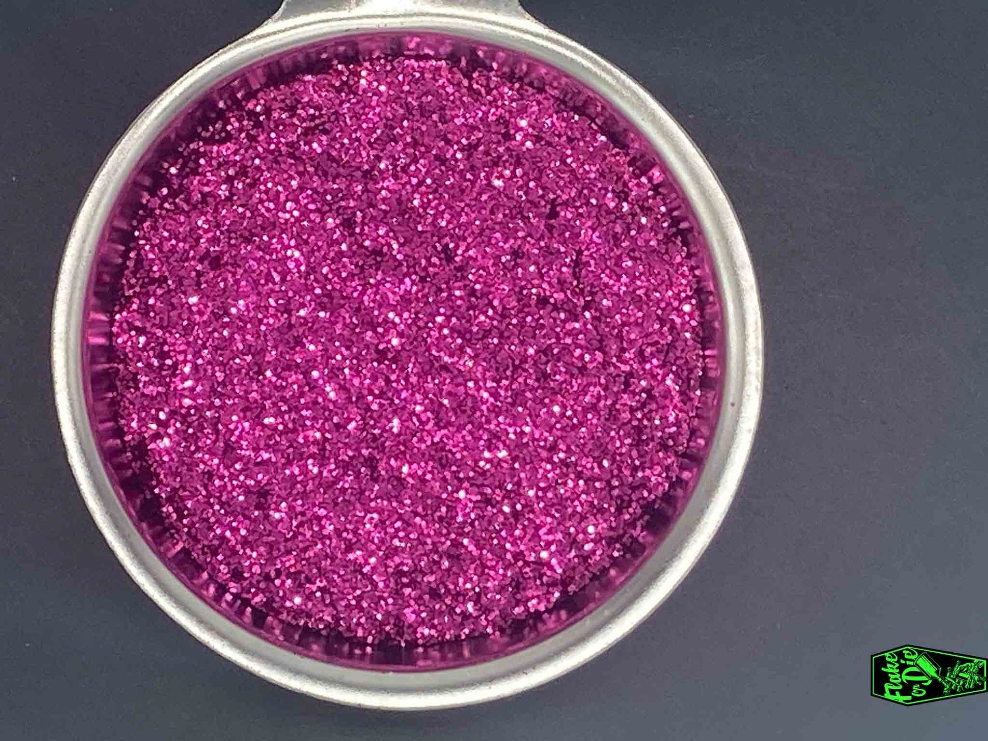 Direct macro photography shot of magenta metal flake particles in a stainless-steel bowl.