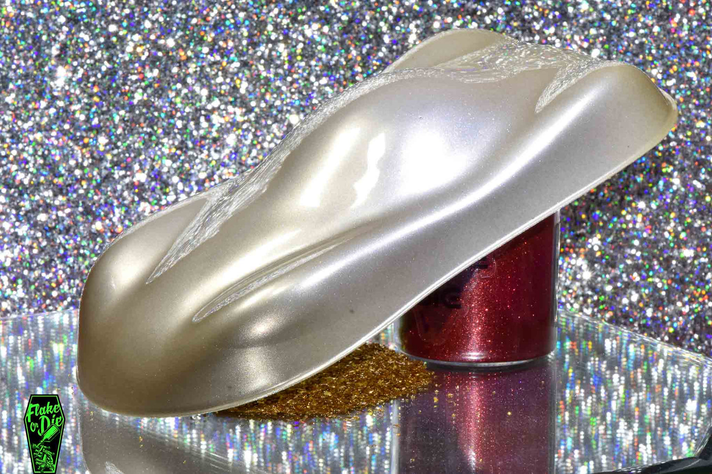 Macro photography of a car like speed shape painted with dull brass pearl pigment. Lighting contrasts of titanium silver and brass on the curves of the shape. Mirrored platform and complementary background of silver bokeh.