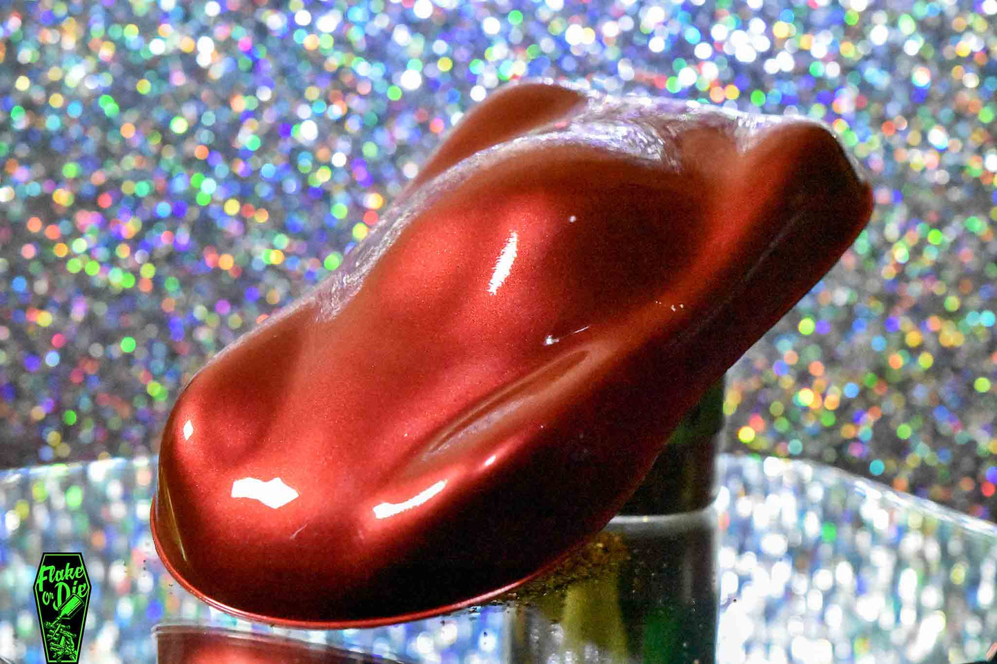 Macro photography of a car like speed shape painted with metallic red pearl pigment. Lighting contrasts of dark and light reds on the curves of the shape. Mirrored platform and complementary background of silver bokeh.