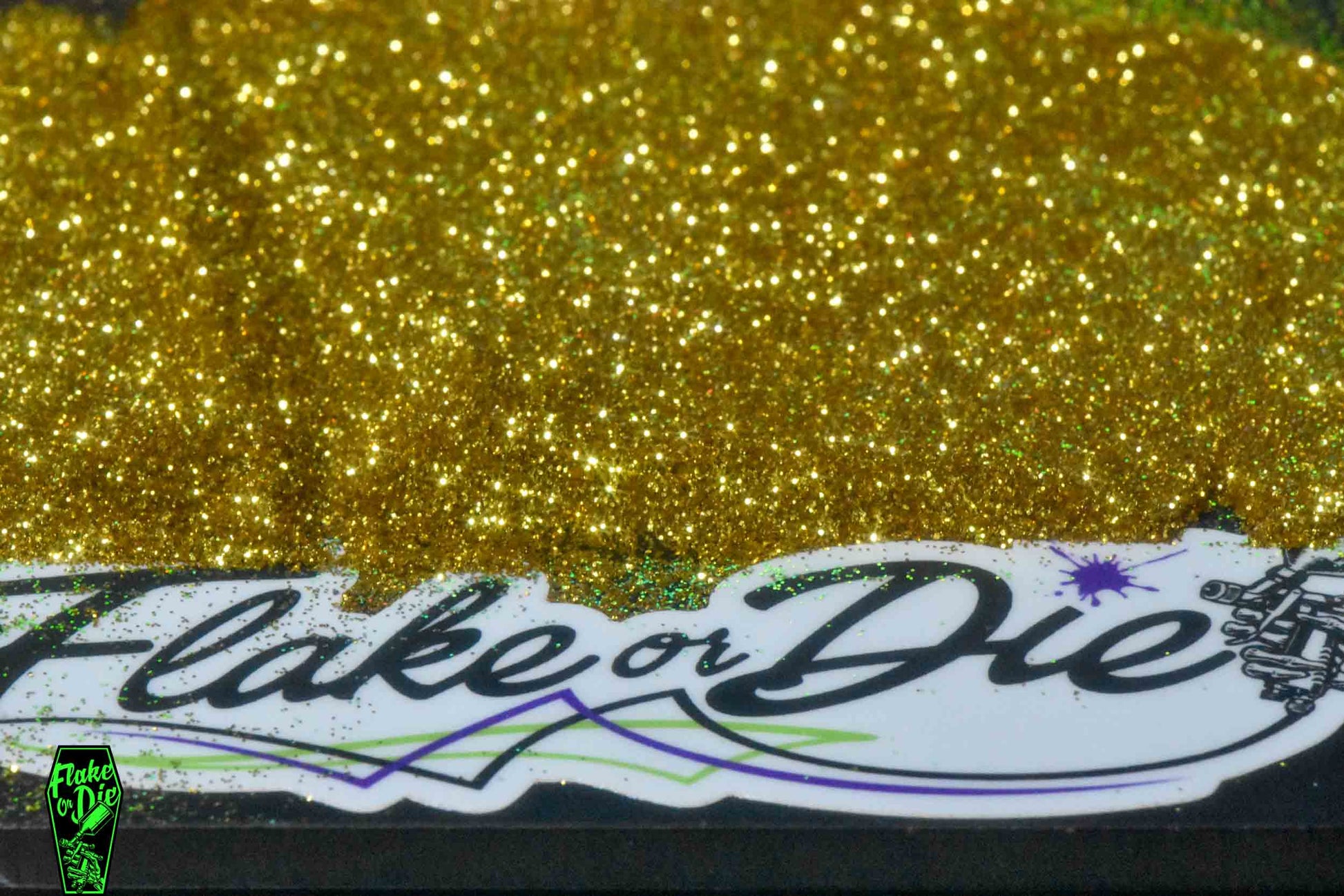 Flake or Die product photography of gold hex cut metal flake spread out over paint splat sticker.