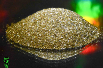 Macro photography of a small pile of gold mirrored glass particles. Distinct glitter flares of gold shards and a complementary holographic background.