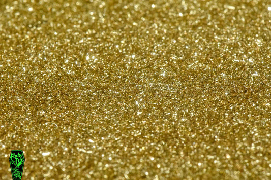 Macro photography product shot of gold glass particles in a small pile.