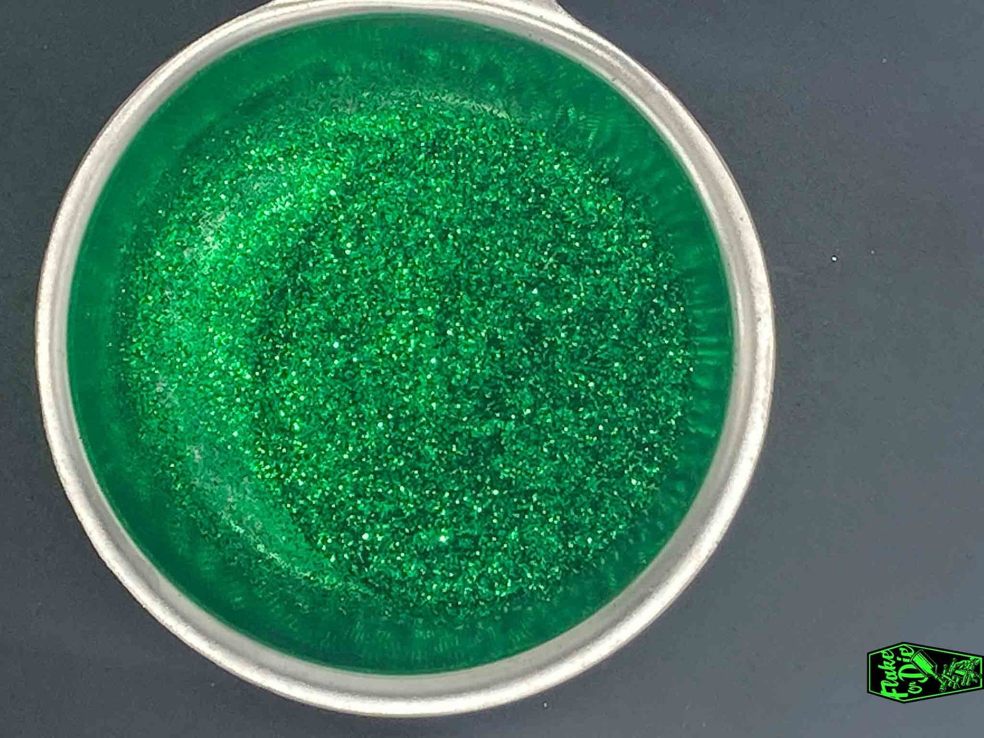 Direct macro photography shot of green metal flake particles in a stainless-steel bowl.