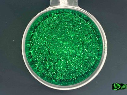 Direct macro photography shot of green metal flake particles in a stainless-steel bowl.