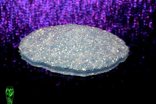 Macro photography of a small pile of white iridescent metal flake particles. Distinct glitter flares on the metal flake and a complementary background with purple bokeh.