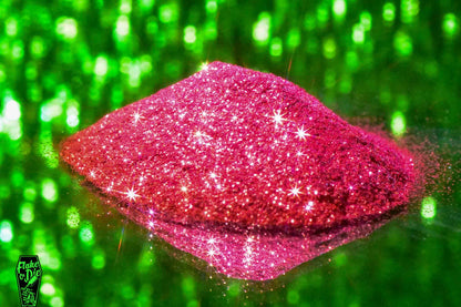 Macro photography of a small pile of red metal flake particles. Distinct glitter flares on the metal flake and a background of green bokeh.