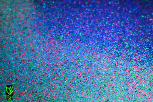 Macro photography of a small pile of blended magenta, green, blue metal flake particles.