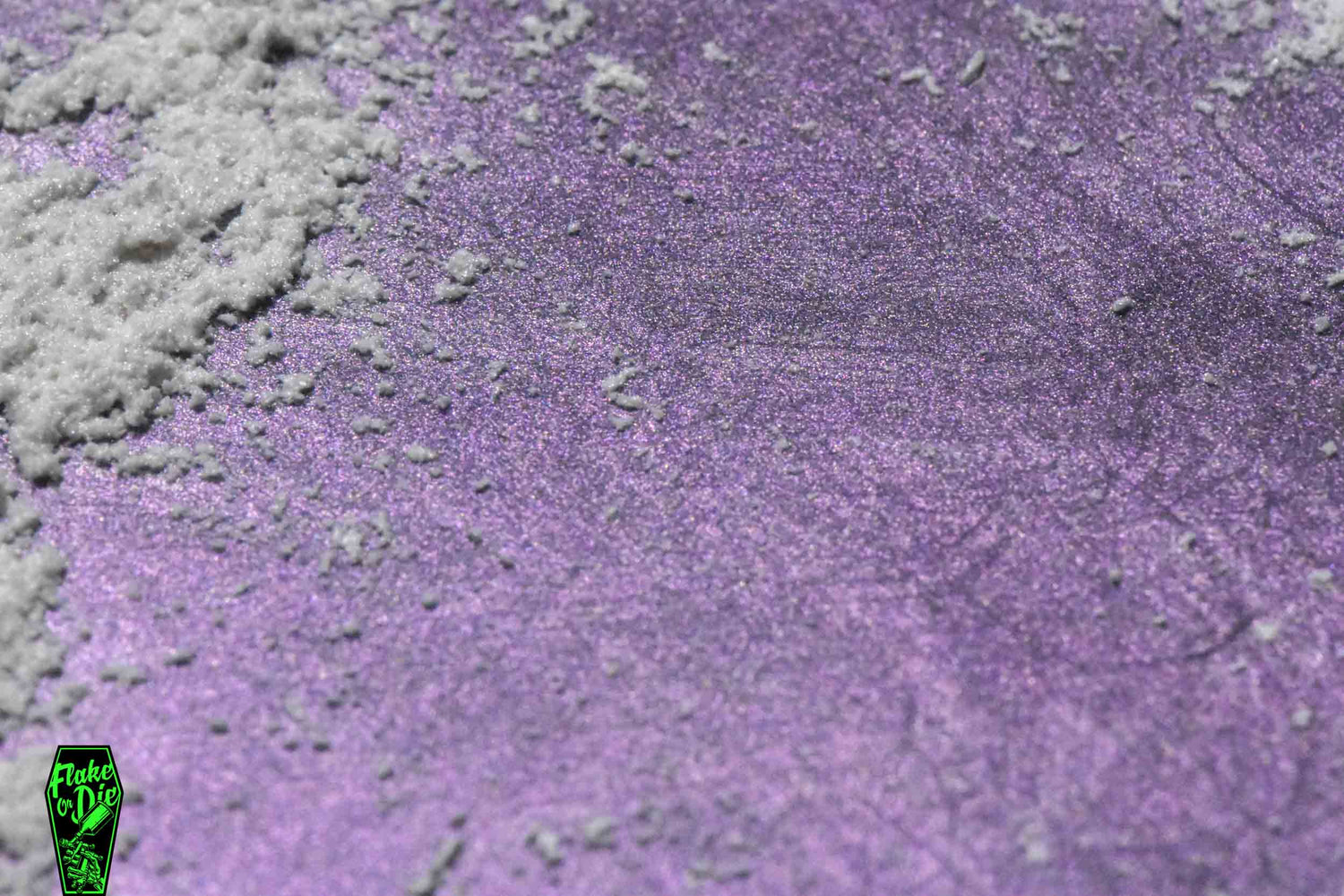 Product photo of white/purple ghost pearl pigment power smeared on a black board.