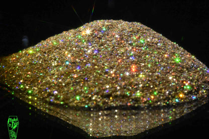 Macro photography of a small pile of blended gold holographic metal flake particles. Distinct glitter flares of gold, purple, green and orange on the metal flake.