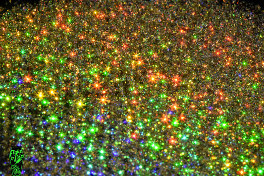 Macro photography of blended gold holographic metal flake particles. Distinct glitter flares of gold, purple, green and orange on the metal flake.