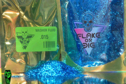 Product shot of Flake or Die blue metal flake, Washer Fluid .015" hex cut in product packaging. Clear windowed foil reasealable pounch with Logo. Small pile of loose metal flake in front of packaging.